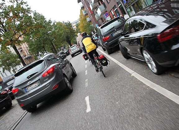 Ein Radfahrer auf einem Schutzstreifen wird mit weniger als 1,5 m Abstand überholt.